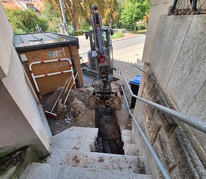 Reparatur der Schulstaffel mit einem großen Loch und und einem Bagger dahinter 