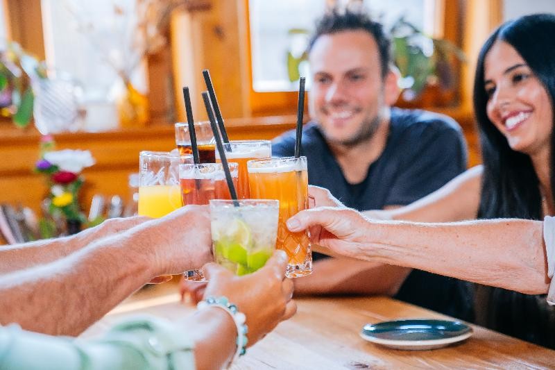 Lachende Gäste stoßen mit Cocktails an.