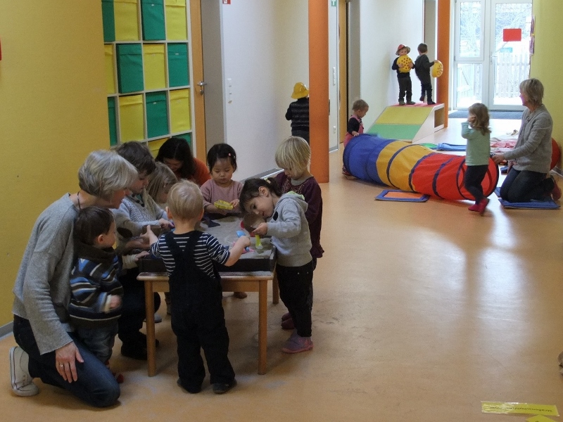 Gruppenraum Kinder stehen um einen Tisch