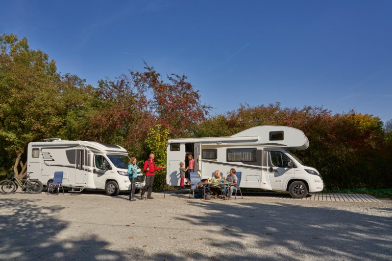 Zwei Wohnmobile parken nebeneinander auf einem Stellplatz.
