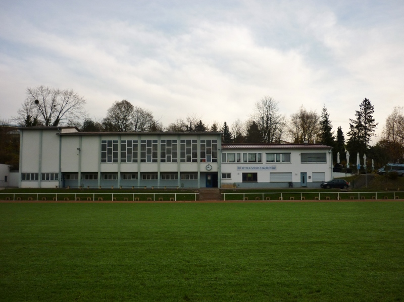 Ansicht eines Gebäudes vor einem Fußballplatz mit Rasen